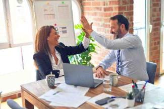 Two people at work high fiving at a desk